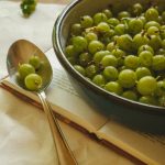 green gooseberry fruits in a bowl and spoon